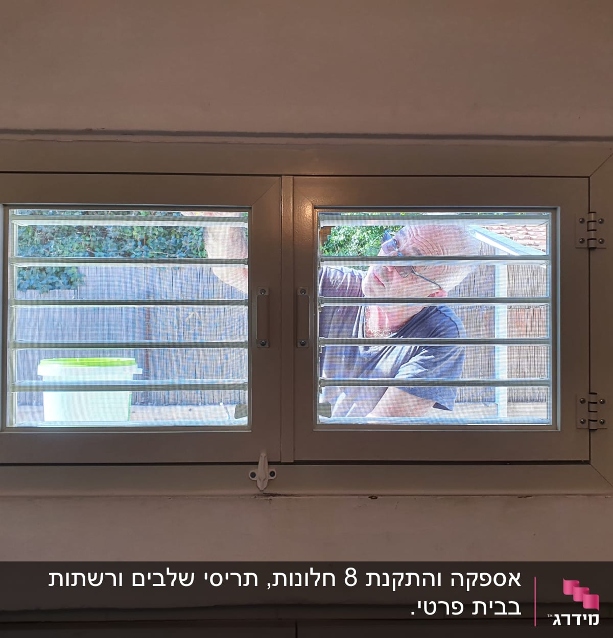 אדם עובד על תריסי אלומיניום בחלון